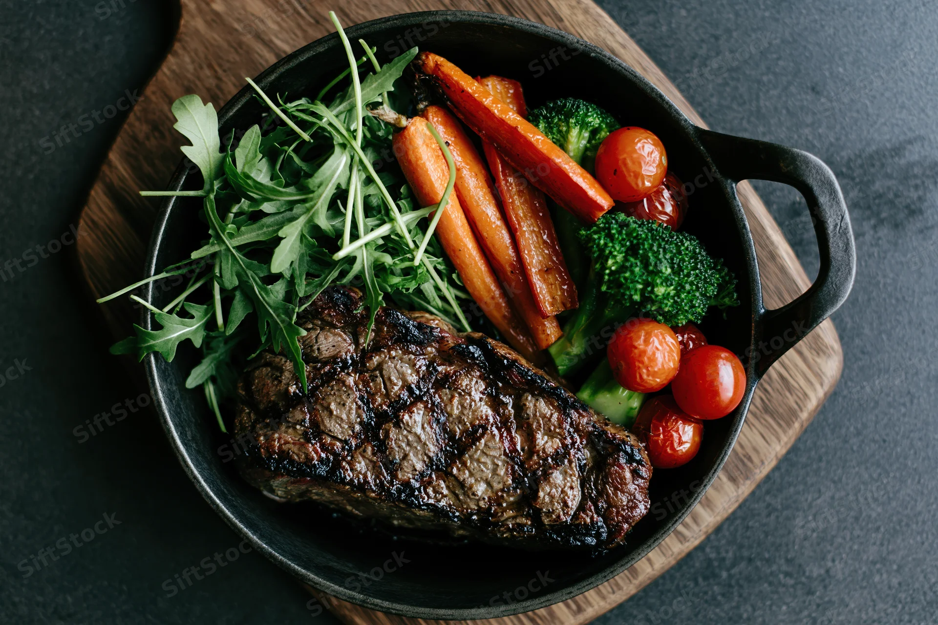 Grilled beef steak with vegetables in a cast iron skillet on a wooden board