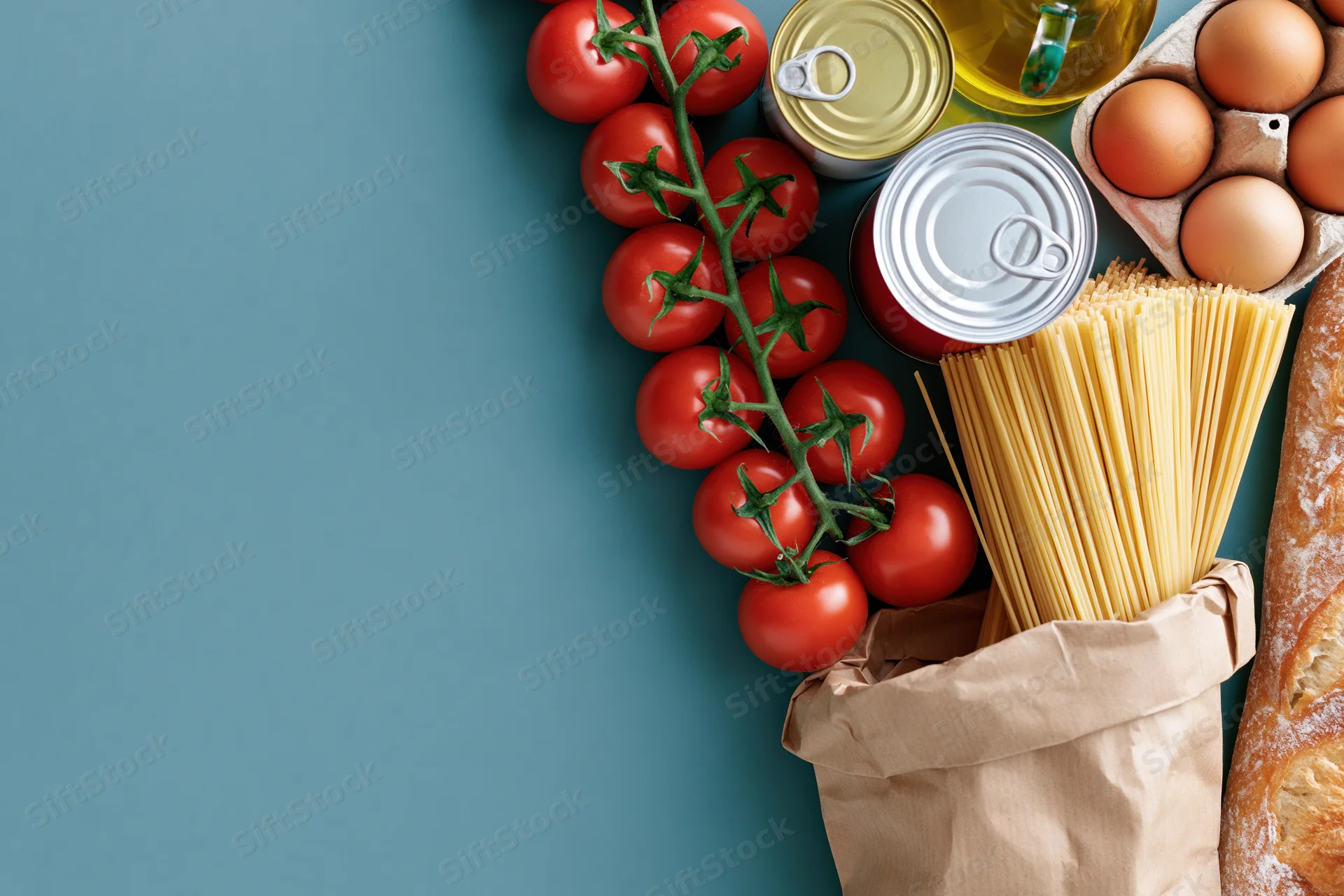 Grocery staples arranged along right edge of flat lay with copyspace on left