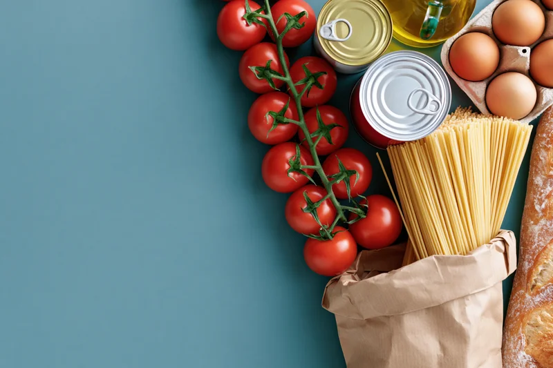 Grocery staples arranged along right edge of flat lay with copyspace on left