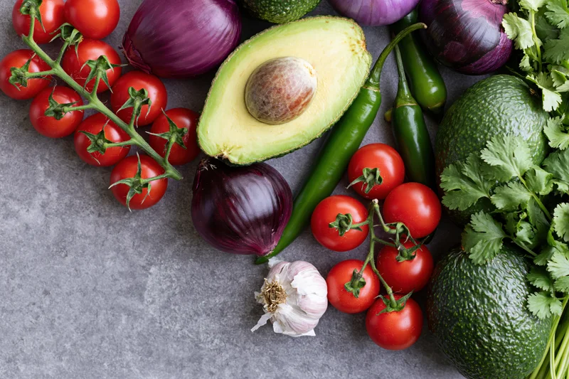 Guacamole ingredients arranged on a concrete surface with copyspace