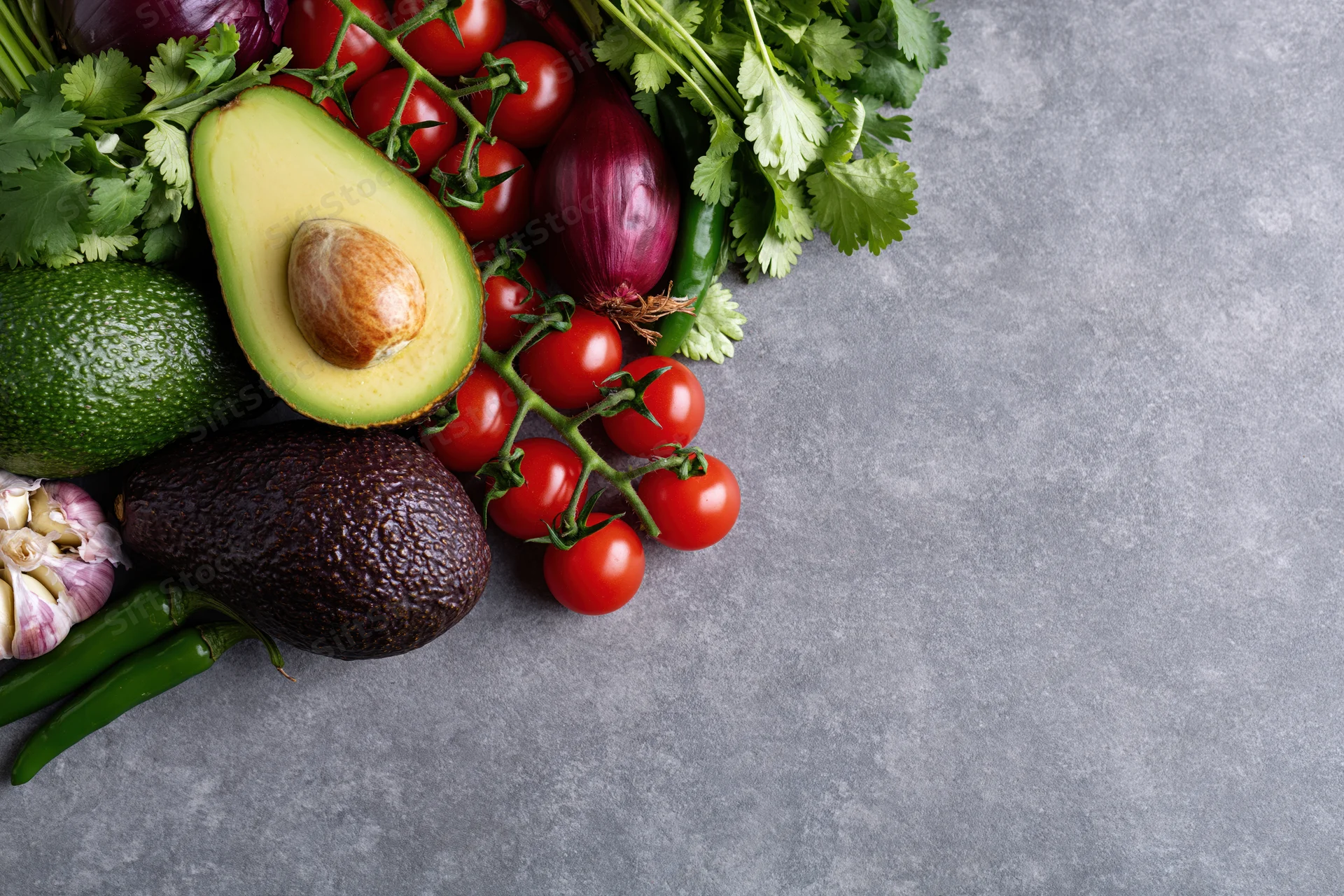 Guacamole ingredients arranged on a gray concrete surface with copyspace