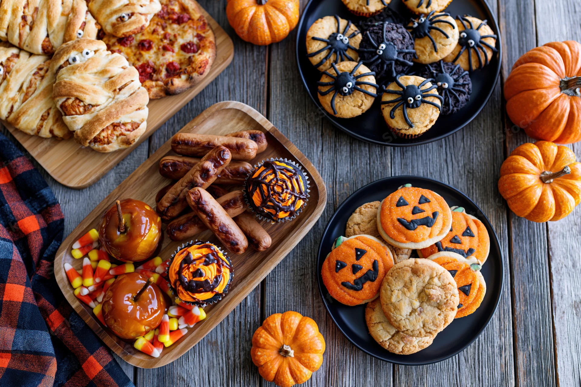 Halloween party food spread with themed desserts and snacks on a rustic wooden table