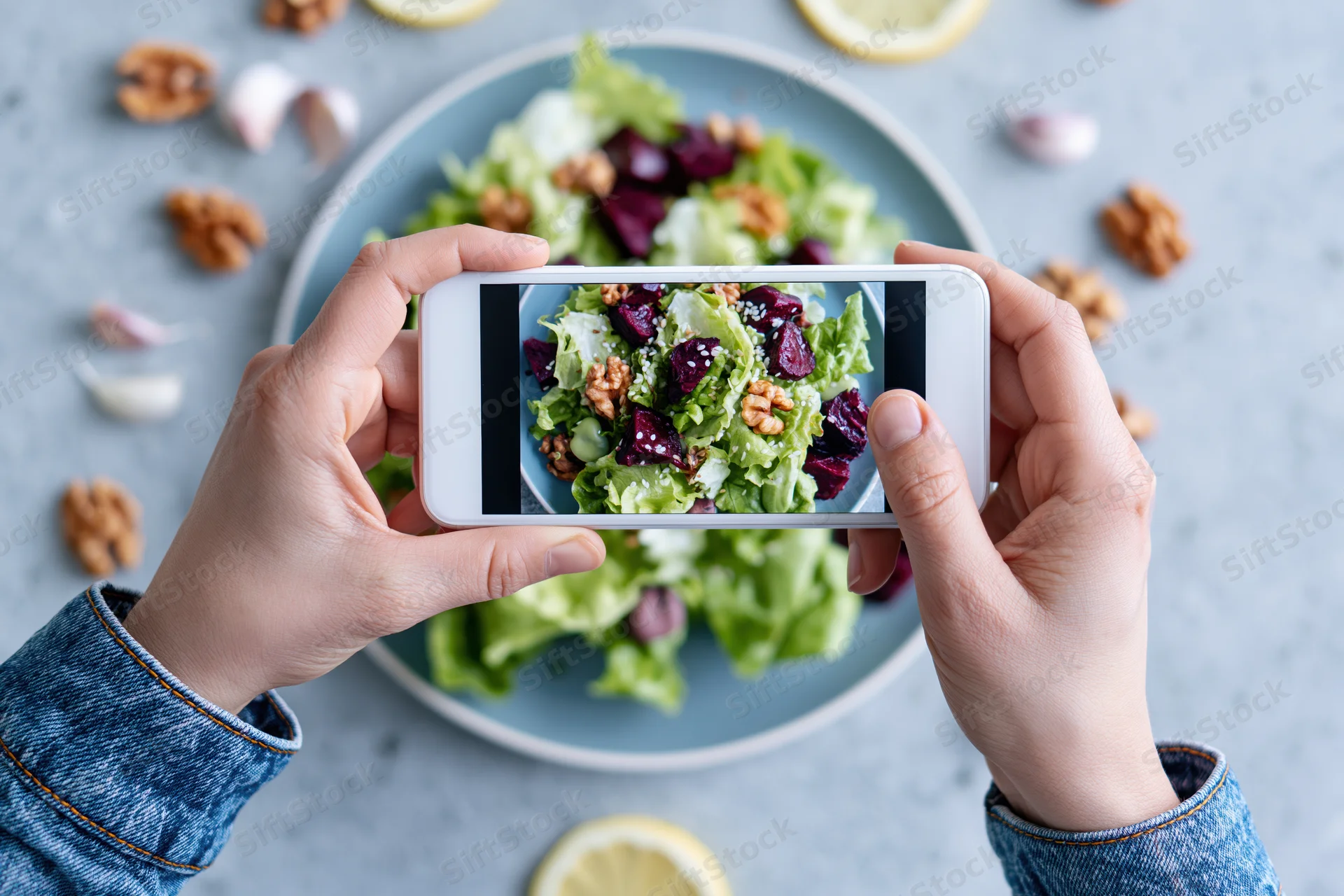Hands holding smartphone photographing salad on plate with walnuts and beets