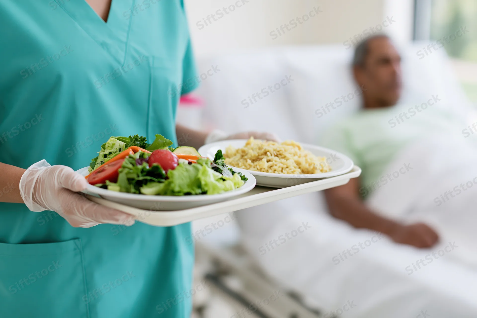 Nurse holding a tray with salad and rice for a patient in a hospital bed