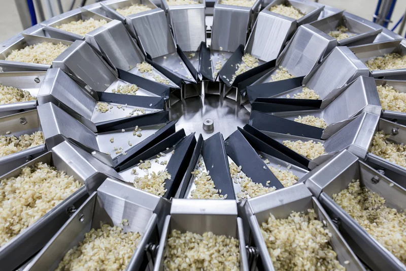 Industrial multihead weigher machine dispensing dry rice grain in a food processing facility