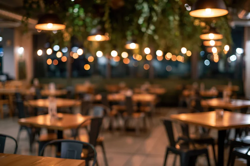 Modern restaurant interior with wooden tables and pendant lights at night
