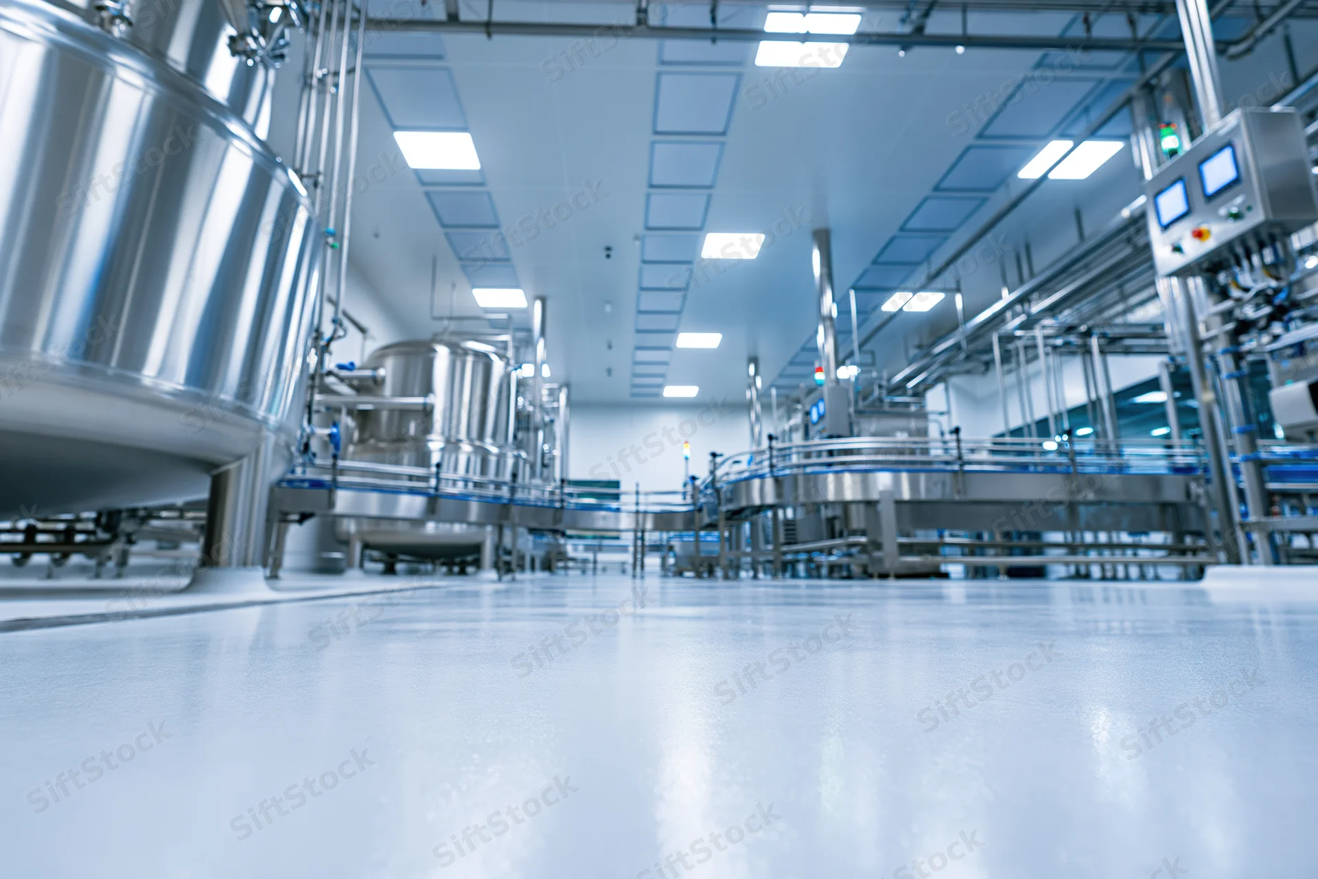Interior of a modern pharmaceutical or dairy processing facility with stainless steel tanks and automated machinery