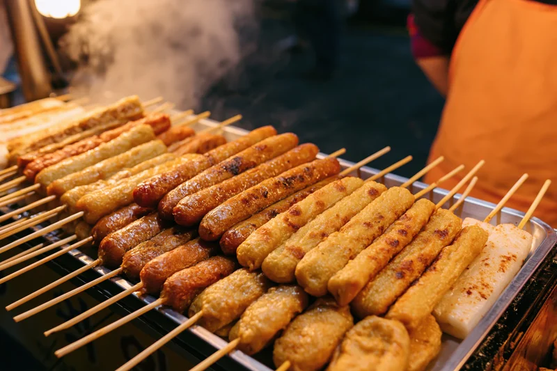 Rows of grilled skewers on a metal tray at a korean street food stall at night