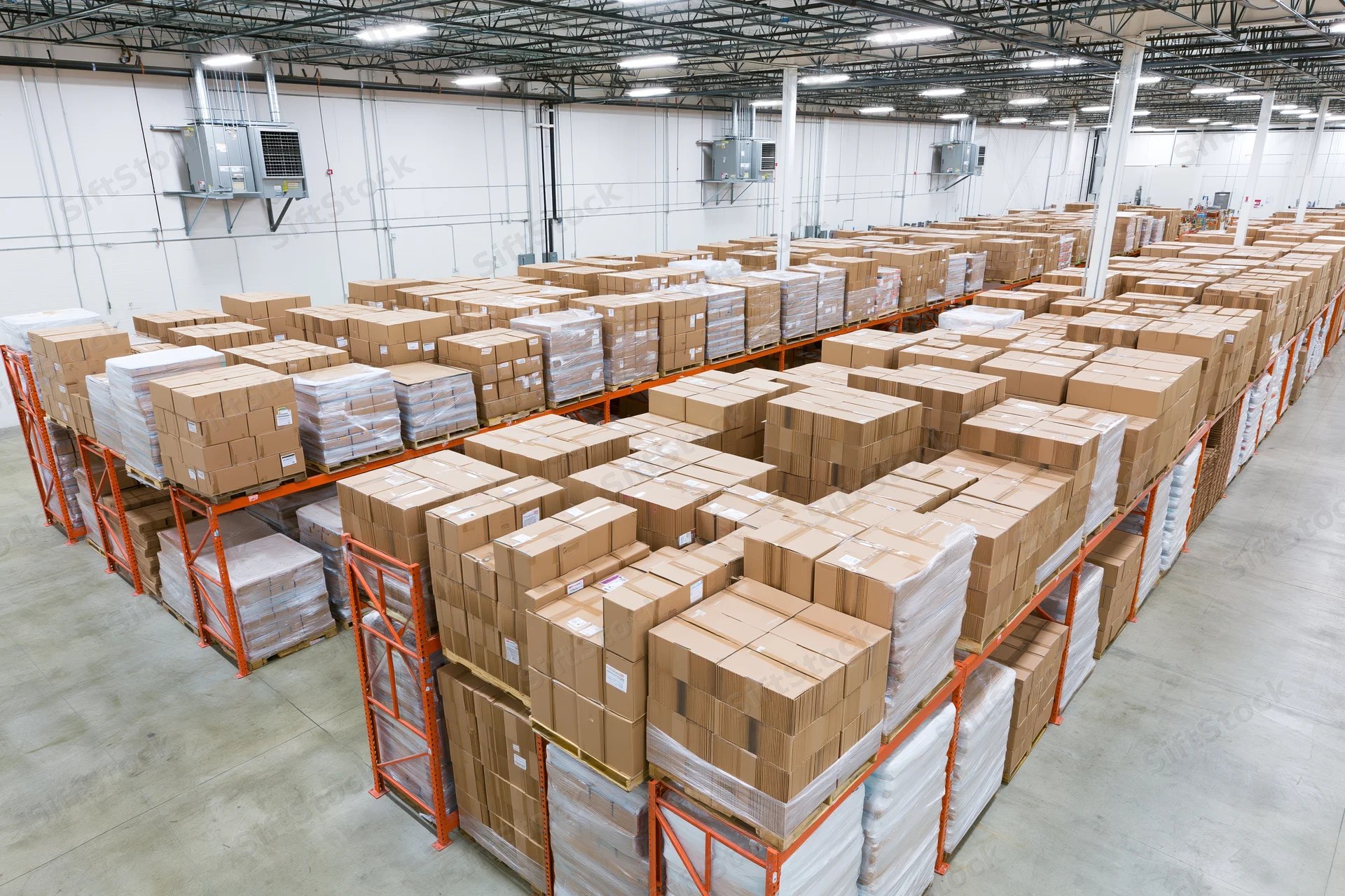 Rows of stacked cardboard boxes on pallets in a large warehouse interior