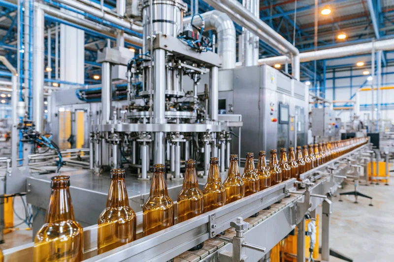 Amber glass bottles moving along conveyor in industrial bottling factory