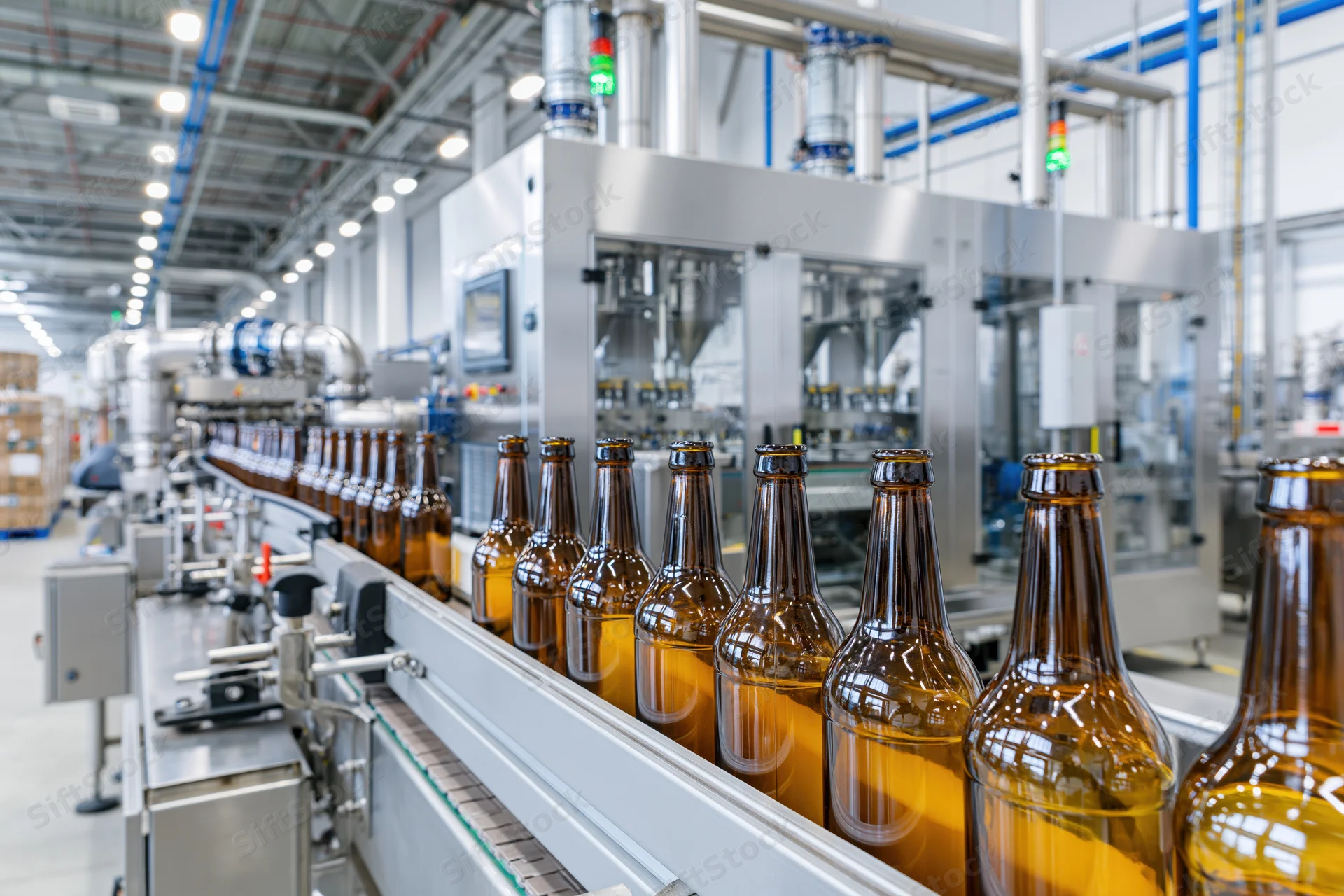 Amber glass beer bottles moving along conveyor in industrial bottling plant