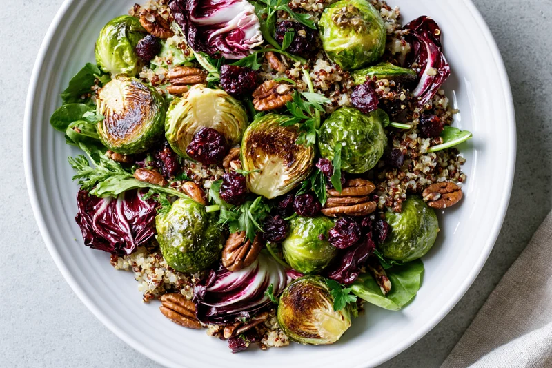 Roasted brussels sprouts salad with quinoa and pecans in a white ceramic bowl