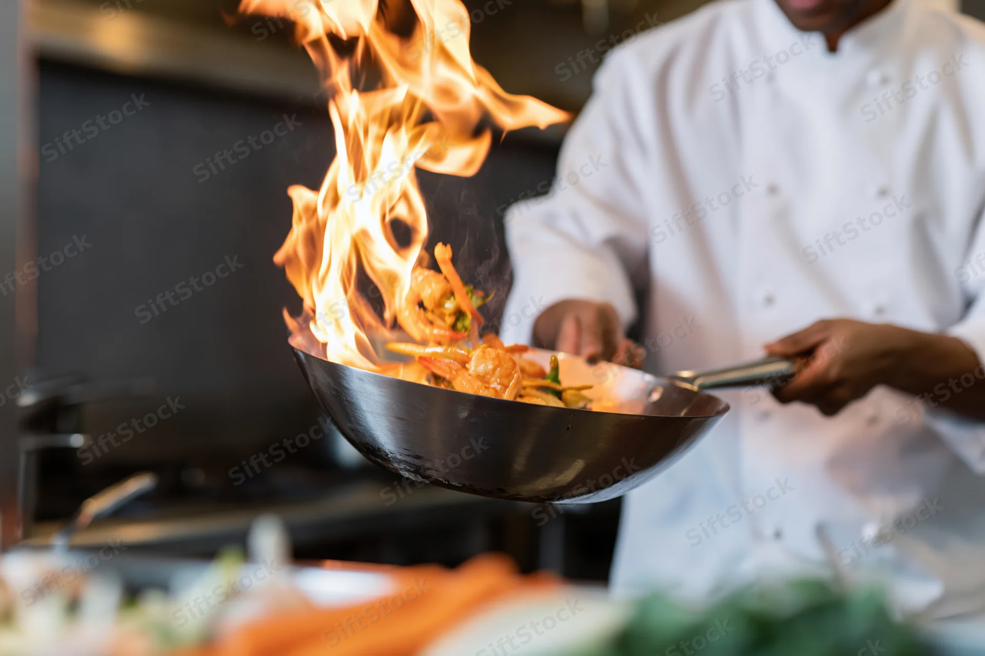 Chef flambéing shrimp in a wok in a restaurant kitchen