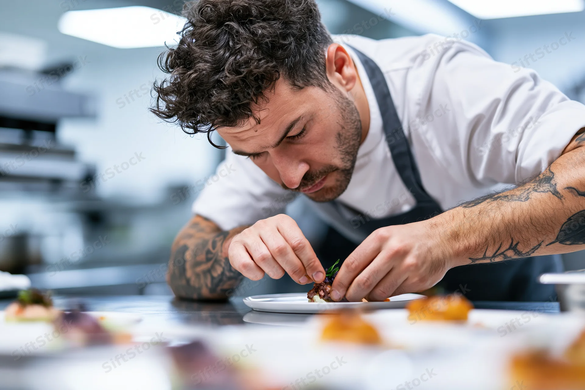 Male chef concentrating on garnishing a dish in a professional kitchen