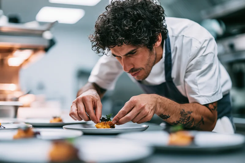 Male chef concentrating on plating a dish in a professional kitchen