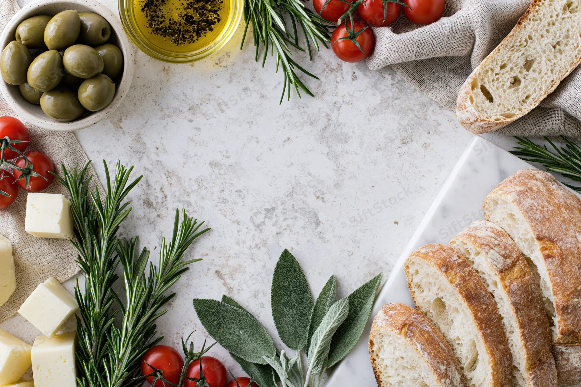 Mediterranean food ingredients arranged in a loose border around a white marble surface with copyspace in center