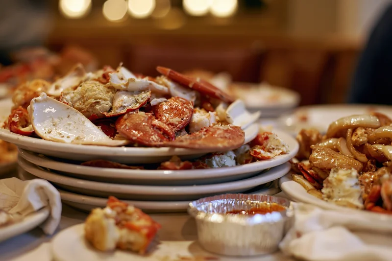 Messy seafood leftovers on white plates at a restaurant dining table