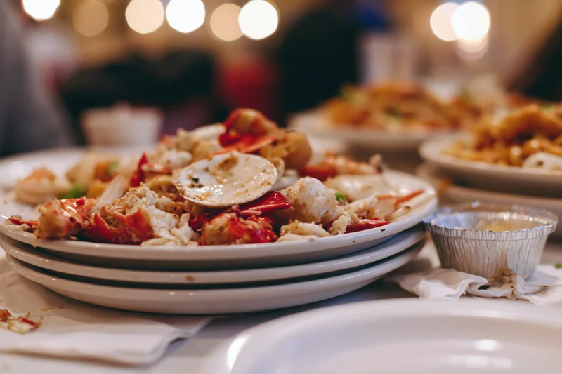 Messy seafood leftovers on stacked white plates at a restaurant dining table