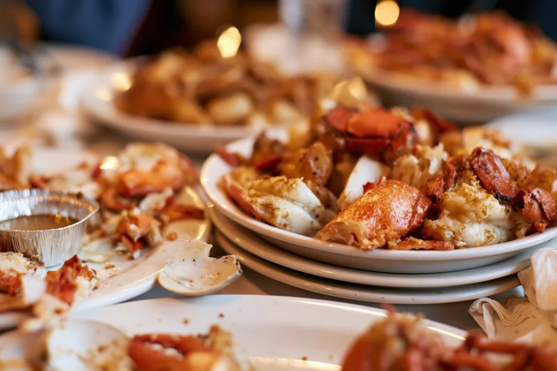 Plates of leftover lobster and shellfish on a dining table after a meal