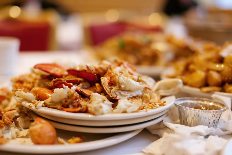 Messy seafood leftovers on white plates at a restaurant dining table