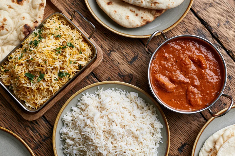 Indian dishes including curry, biryani, and naan arranged on a rustic wooden table