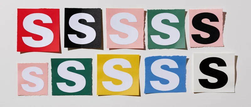 Cut-out letter s clippings arranged in two rows on a white surface