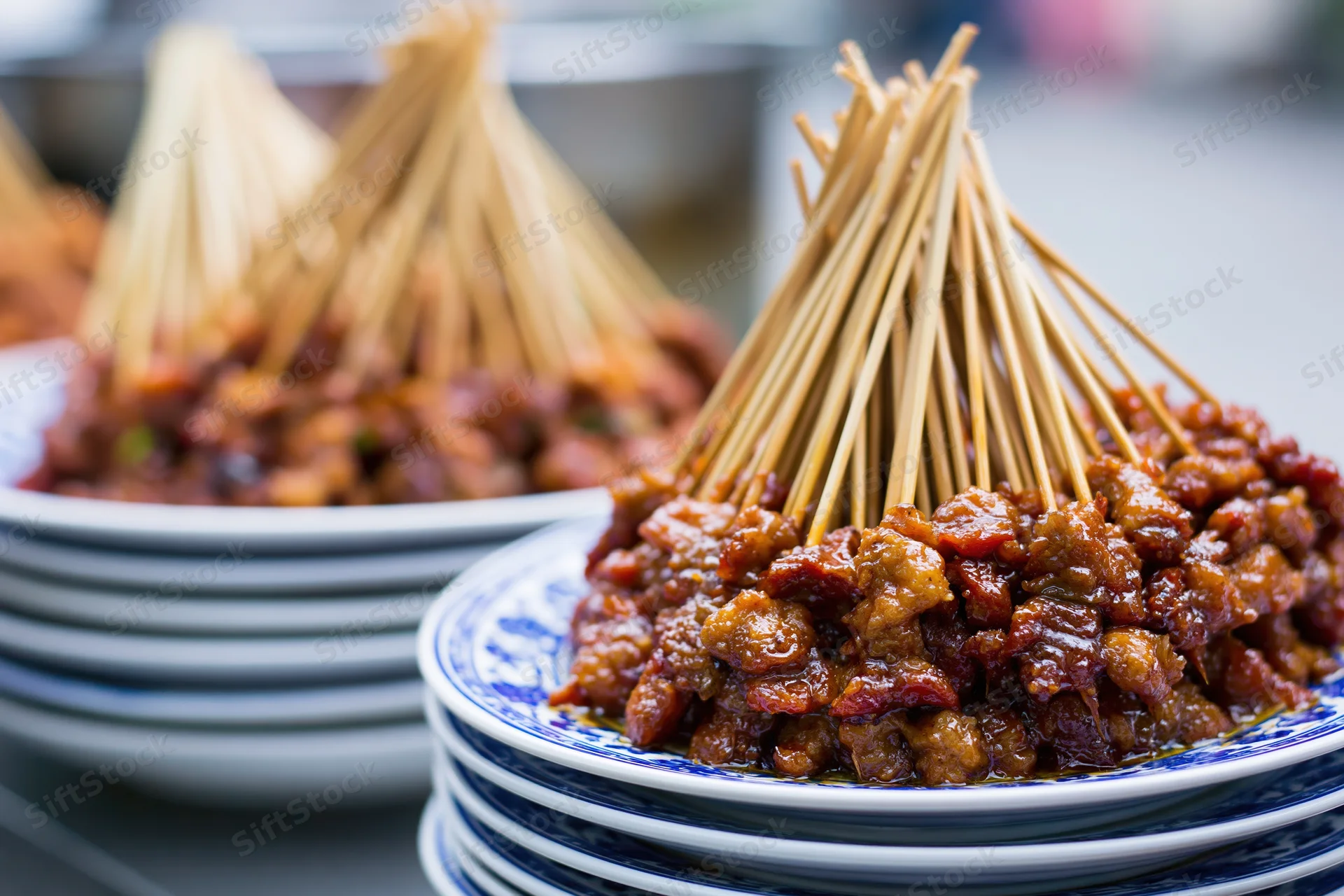 Stacked plates of meat skewers arranged on a table at a street food market