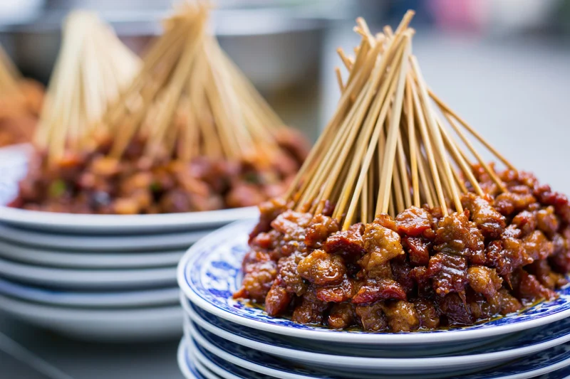 Stacked plates of meat skewers arranged on a table at a street food market