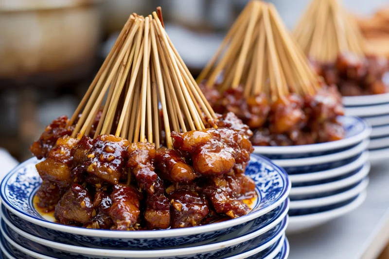 Stacked plates of glazed meat skewers arranged on a table