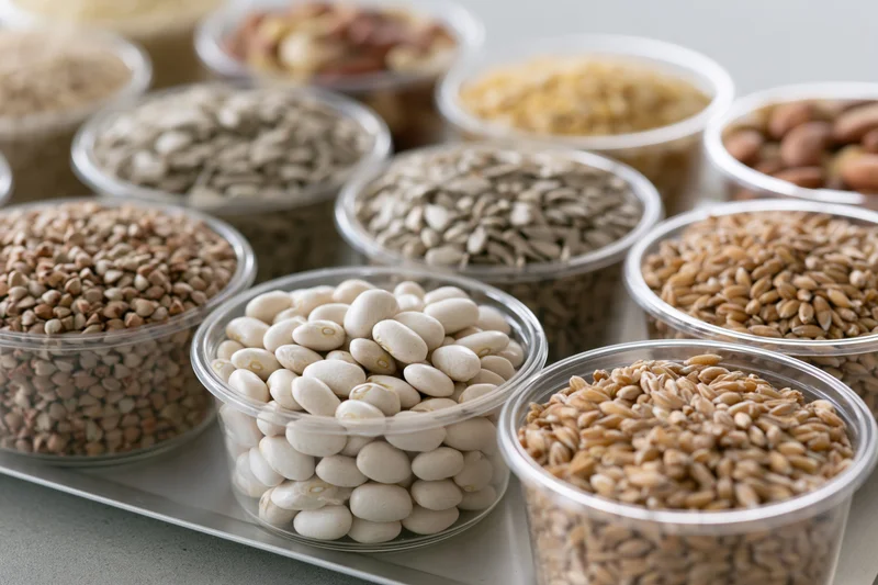 Clear plastic bowls filled with assorted grains and legumes arranged on a tray