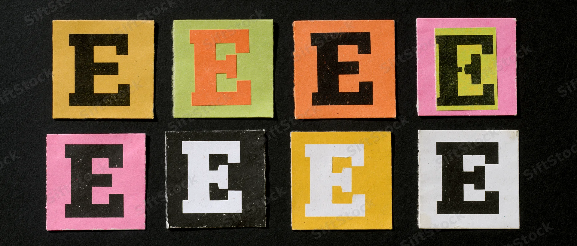 Nine cut-out letter e tiles arranged in two rows on black background