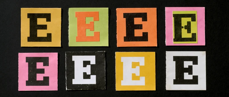 Nine cut-out letter e tiles arranged in two rows on black background