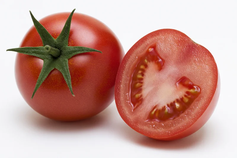 Whole and sliced ripe red tomato with green calyx on white background