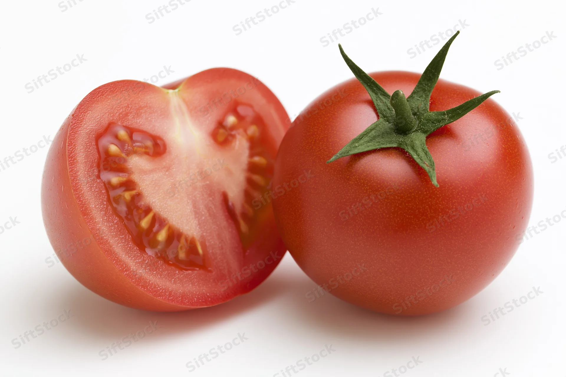 Whole and sliced red tomato with green calyx on white background