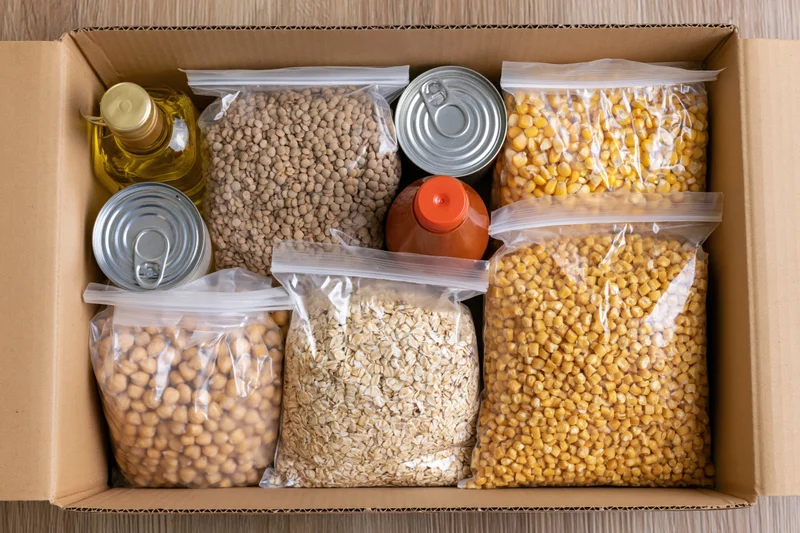 Open cardboard box filled with dry food donation items arranged neatly inside