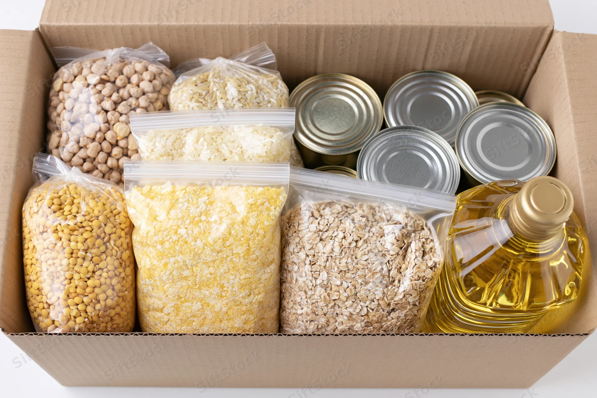 Open cardboard donation box filled with dry goods and canned food for community support
