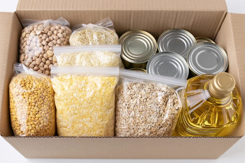Open cardboard donation box filled with dry goods and canned food for community support