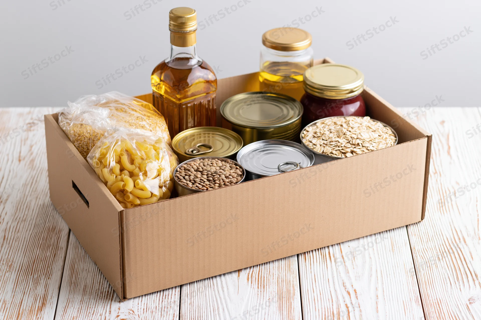 Cardboard donation box filled with dry pantry goods on wooden surface