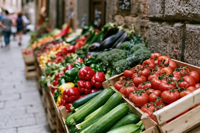Fresh vegetables arranged in wooden crates at an outdoor italian market stall