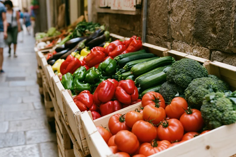 Fresh vegetables arranged in wooden crates at an outdoor italian market stall