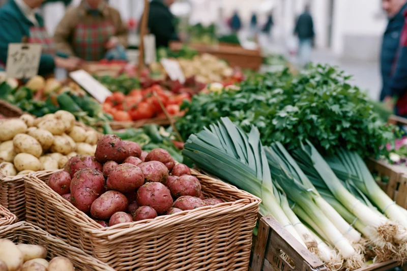 Fresh vegetables in wicker baskets and wooden crates at an outdoor market stall