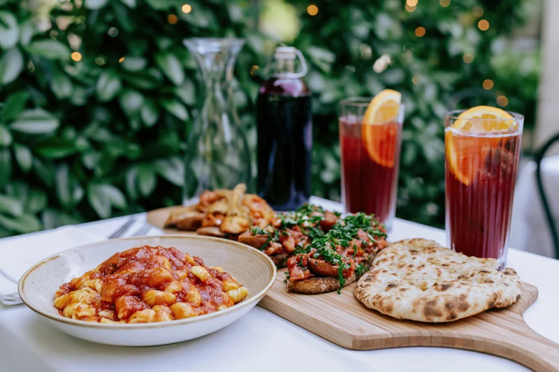 Pasta bowl with bruschetta and flatbread on a table outdoors at a restaurant