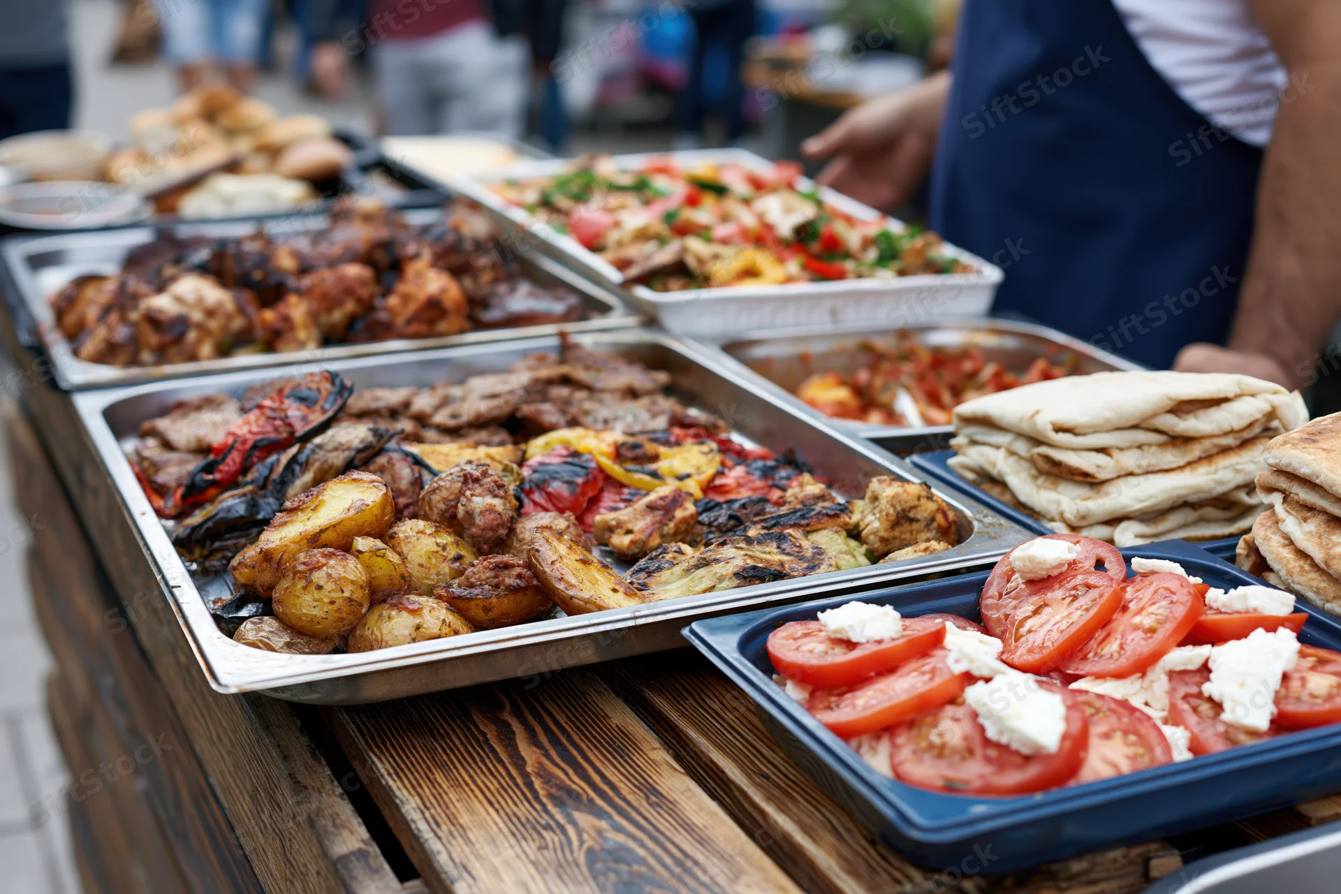 Street food vendor serving grilled meats and vegetables on a rustic wooden table outdoors