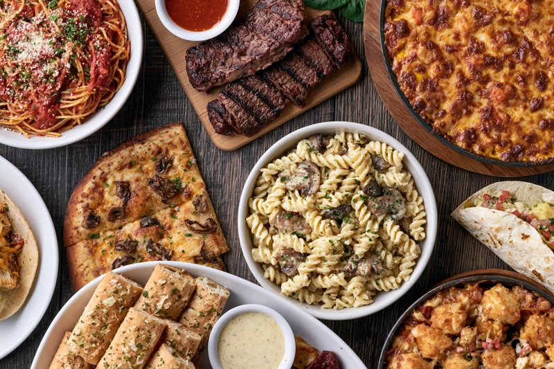 Overhead flat-lay of assorted Italian-American dishes arranged on a wooden table