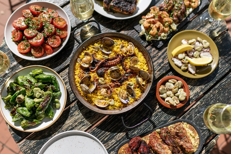 Spanish tapas spread with paella, seafood, vegetables and wine on wooden table