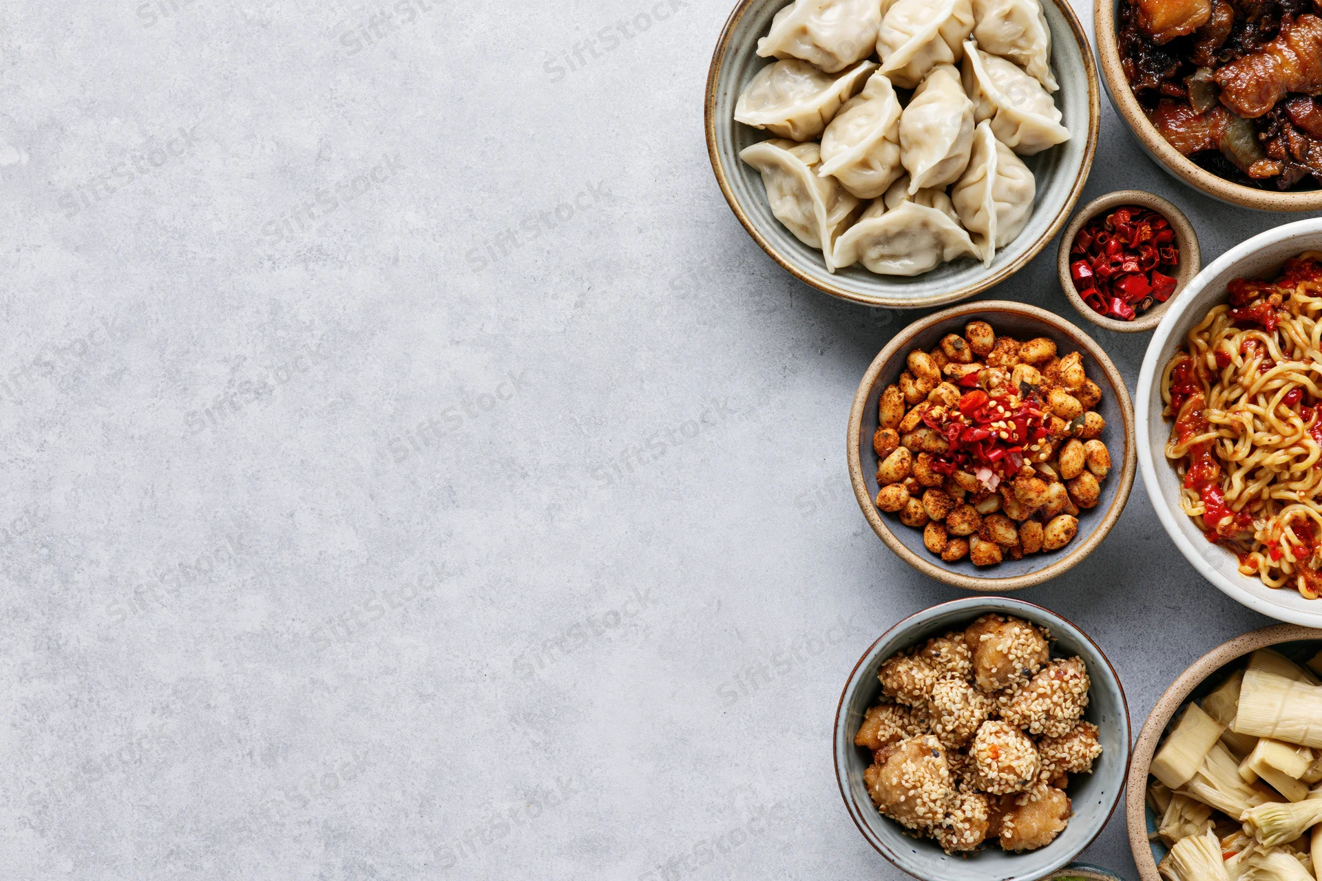 Assorted chinese dishes arranged in bowls on a gray surface in overhead flat-lay view