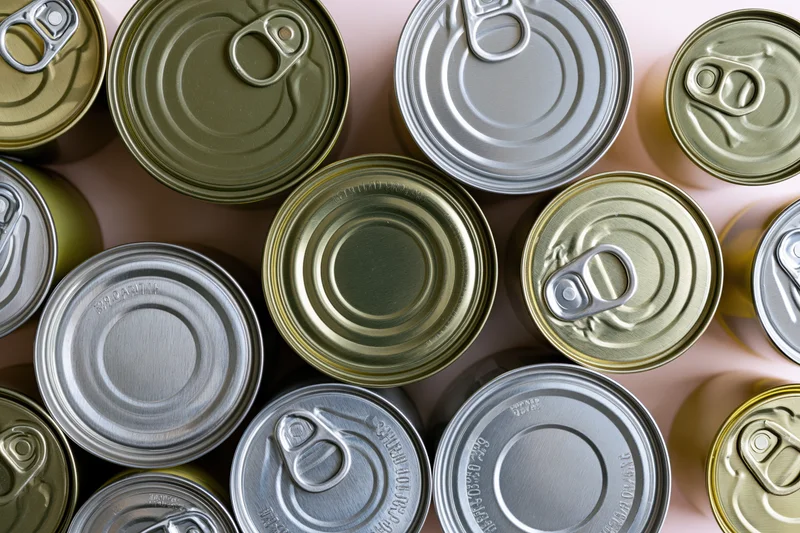Overhead flat-lay of multiple metal food cans arranged closely on a light surface