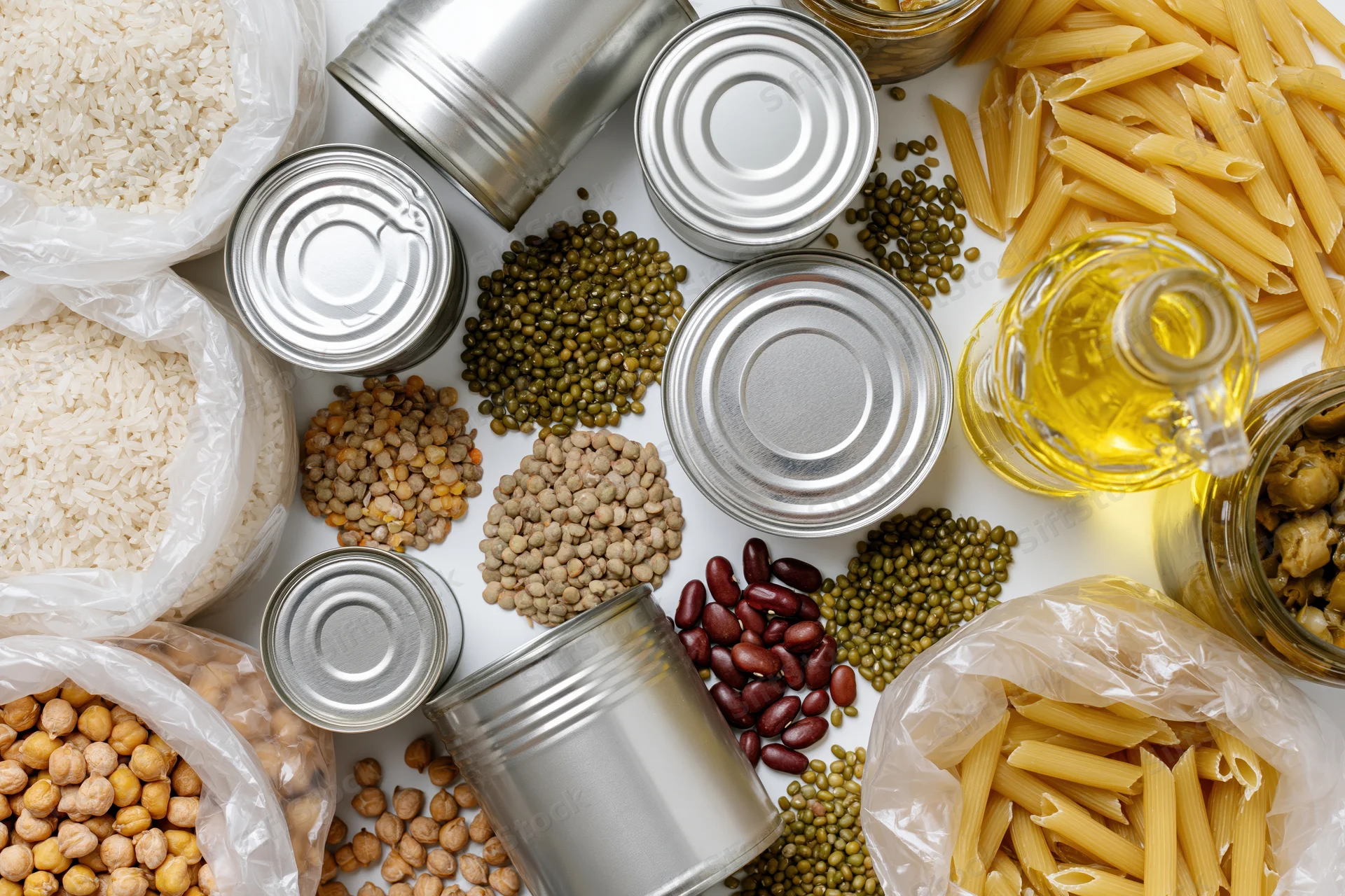 Overhead flat-lay of pantry staples and emergency food supplies arranged on white surface