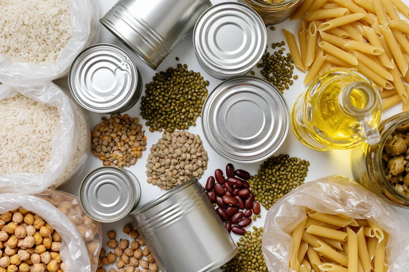 Overhead flat-lay of pantry staples and emergency food supplies arranged on white surface