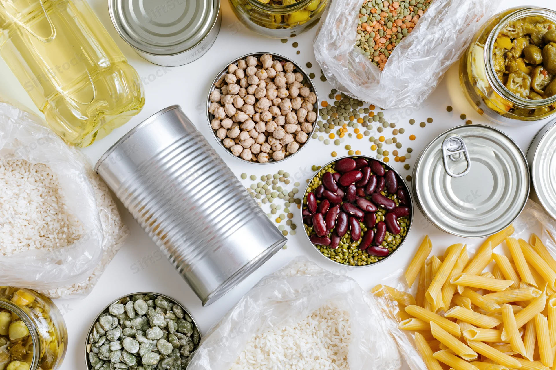 Overhead flat-lay of pantry staples and emergency food supplies arranged on white surface